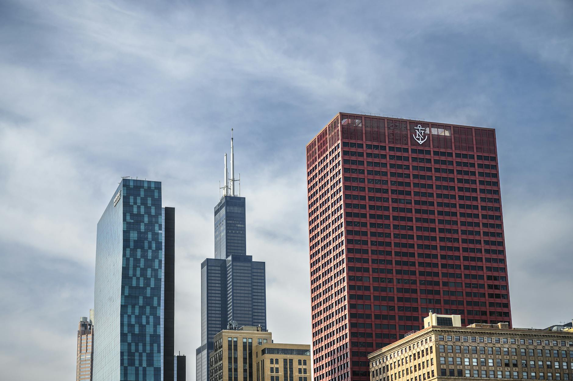 Chicago skyline with Willis Tower and CNA Center under a blue sky with airy clouds.