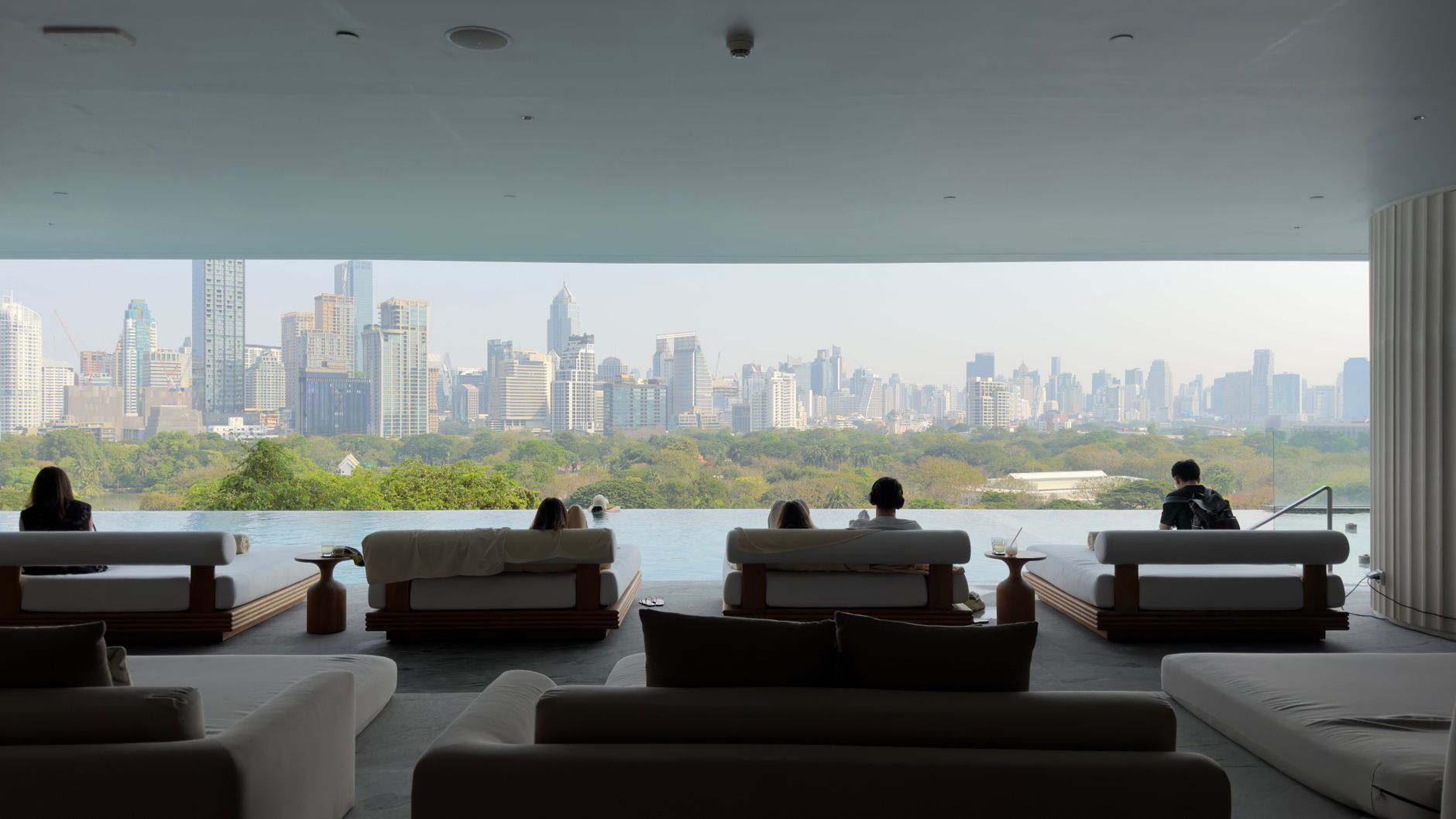 Relaxing view of Bangkok skyline from a luxurious indoor lounge, offering a perfect urban retreat.