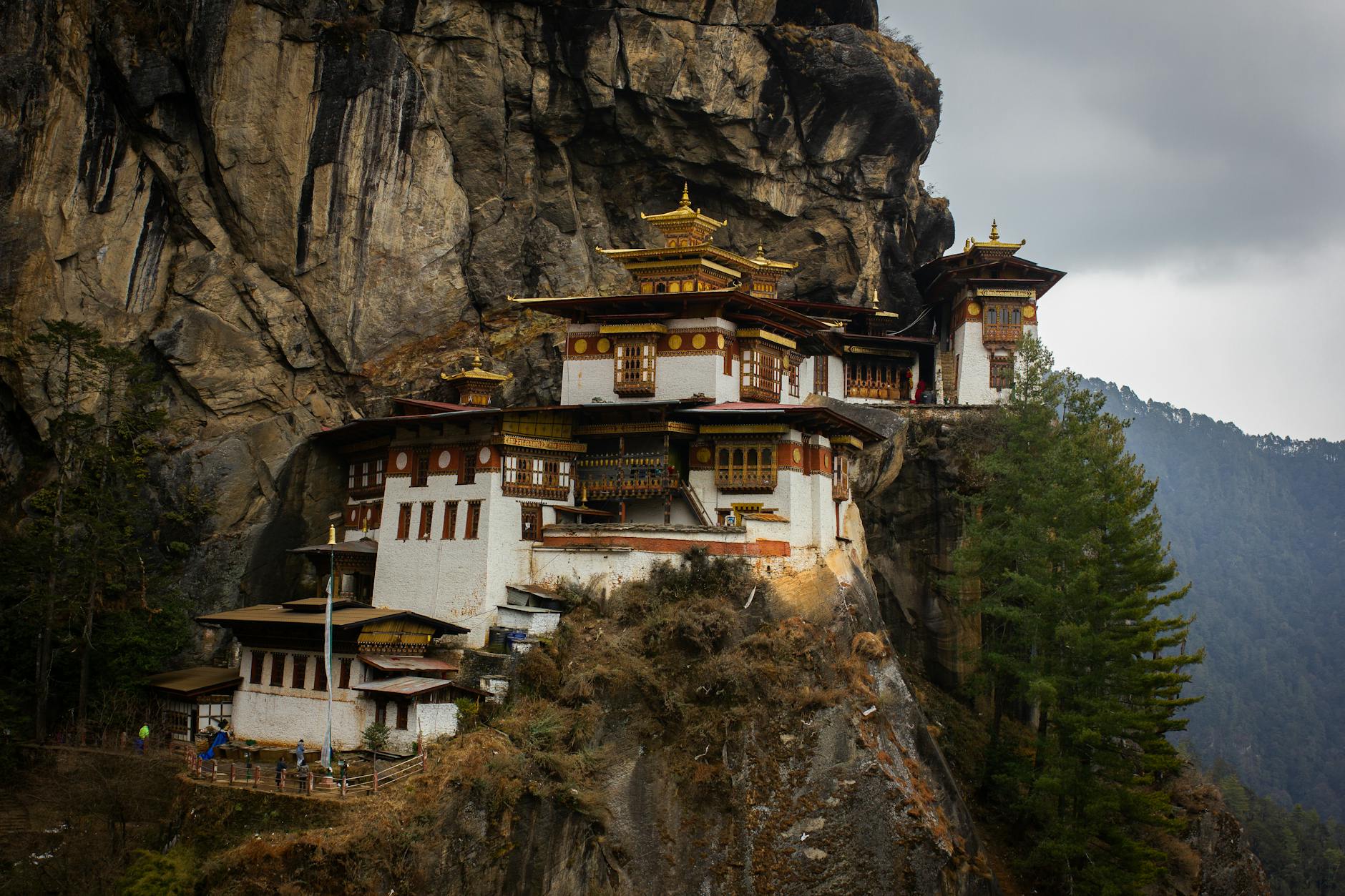 Exterior of Taktsang Lakhang monastery located on stony mountain near green trees under cloudy sky