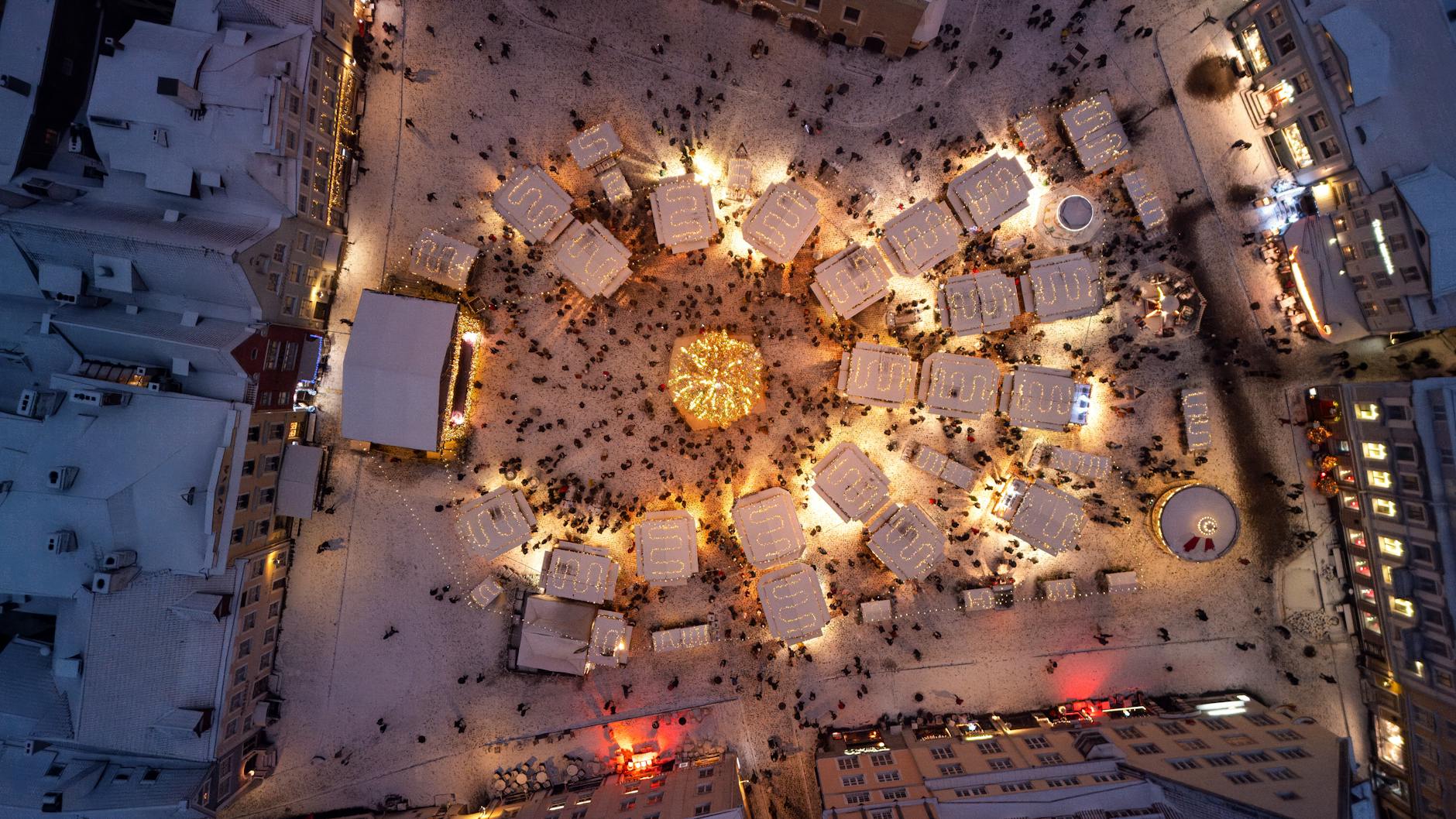 A festive aerial view of Tallinn's Christmas market with beautifully lit stalls and snowy rooftops.