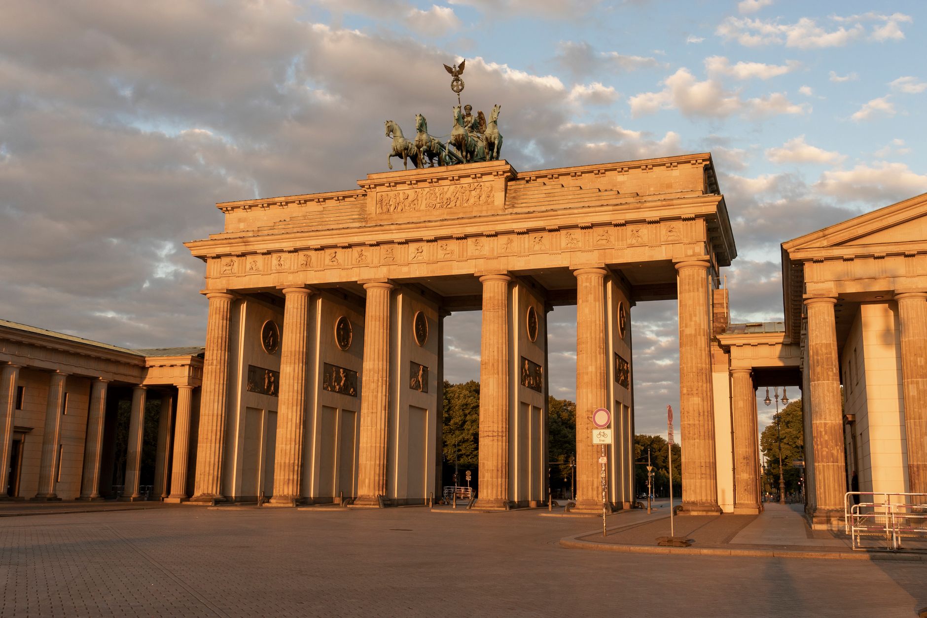 A classic view of the Brandenburg Gate in Berlin, showcasing neoclassical architecture beneath a cloudy sky.