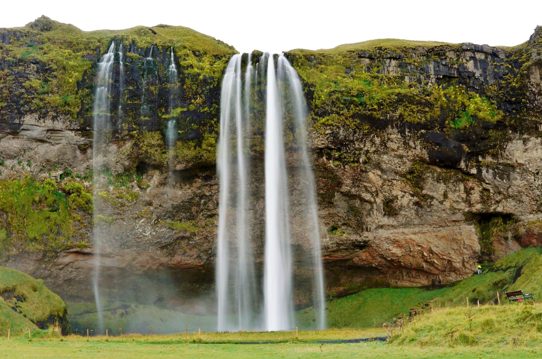 Majestic view of Seljalandsfoss waterfall cascading down rocky cliffs in Iceland's lush landscape.