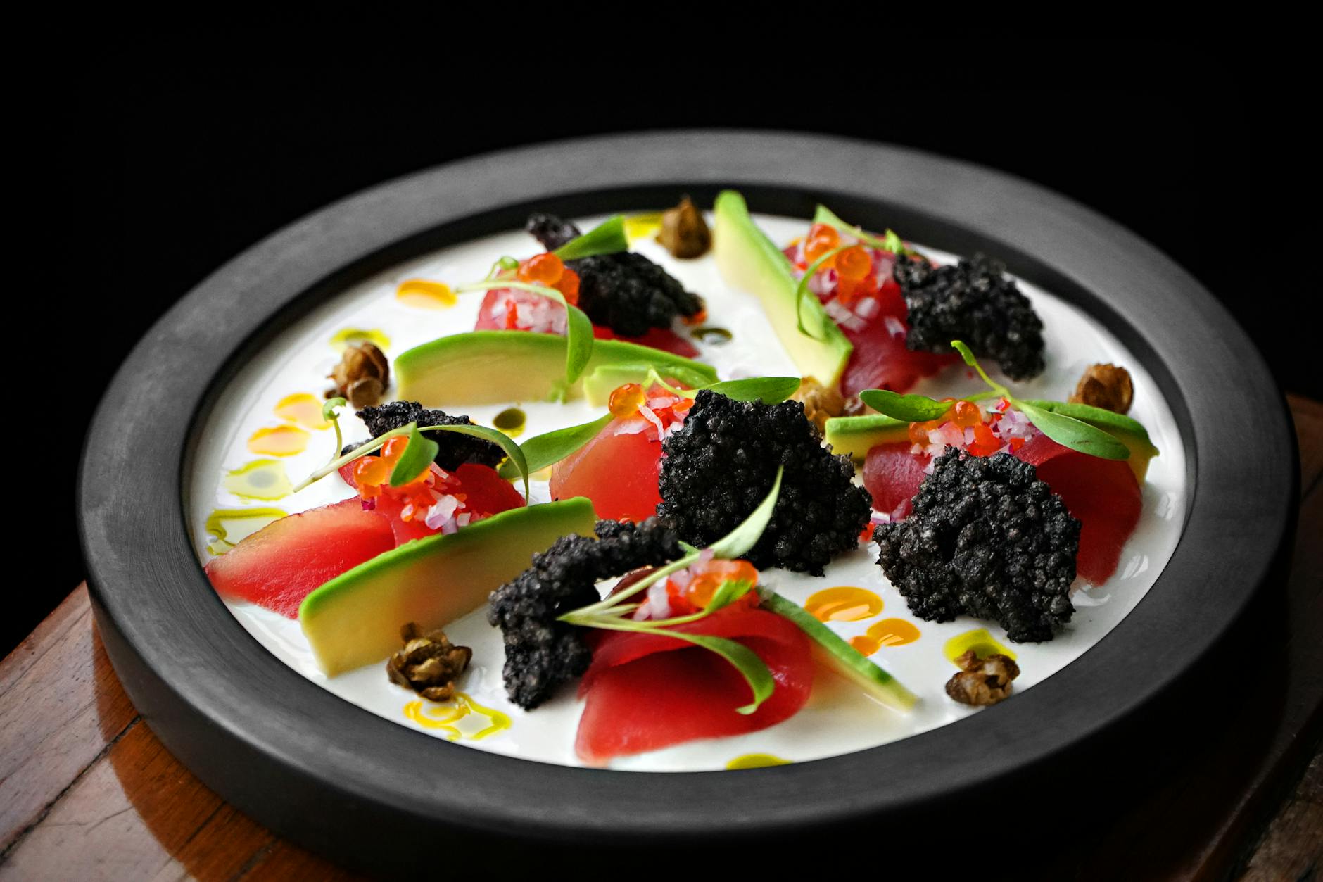 Delicious gourmet ceviche plate with fresh avocado, caviar, and vibrant garnishes.