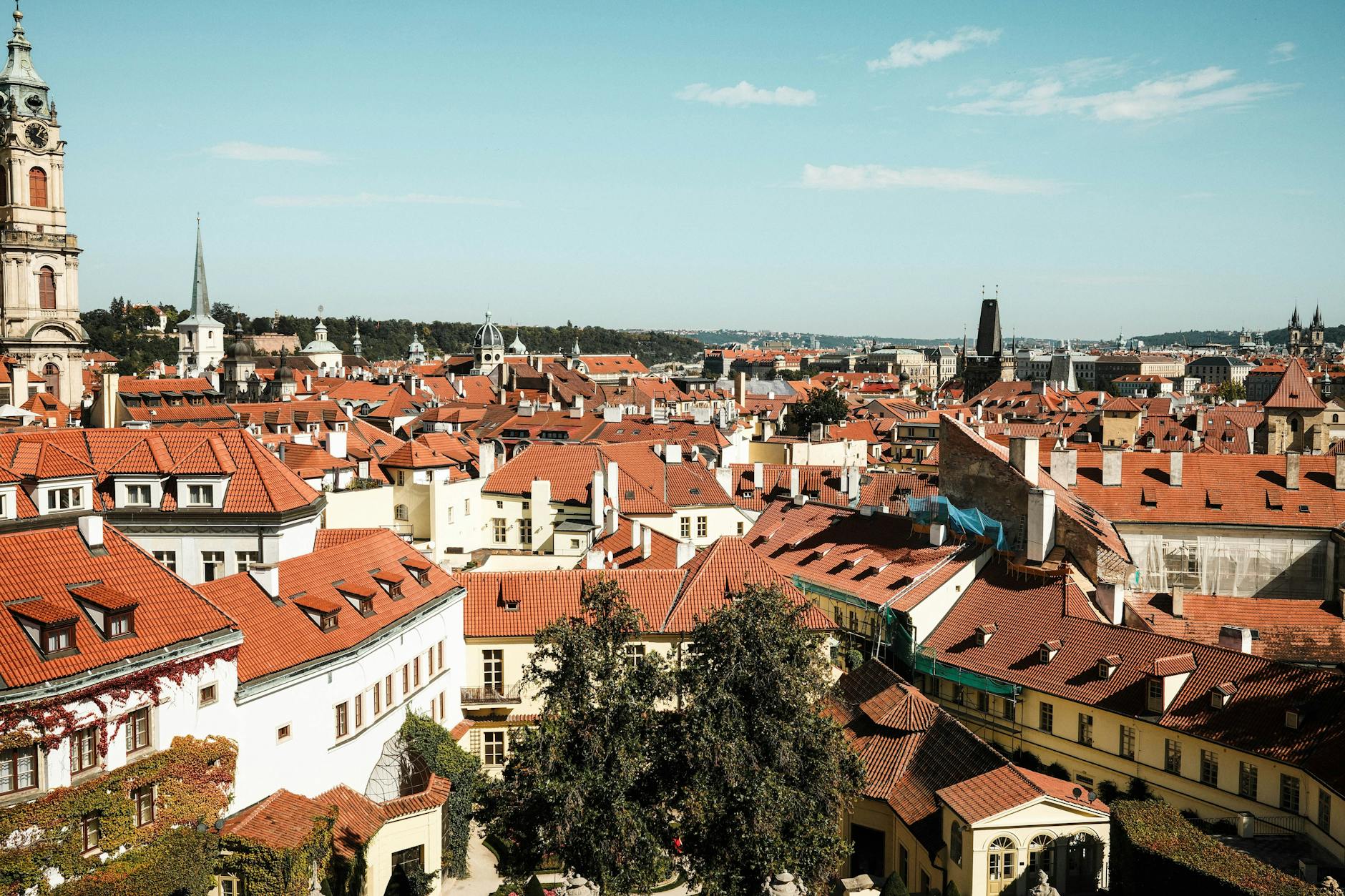 Explore the charming red-tiled rooftops of Prague's historic district under a clear blue sky.