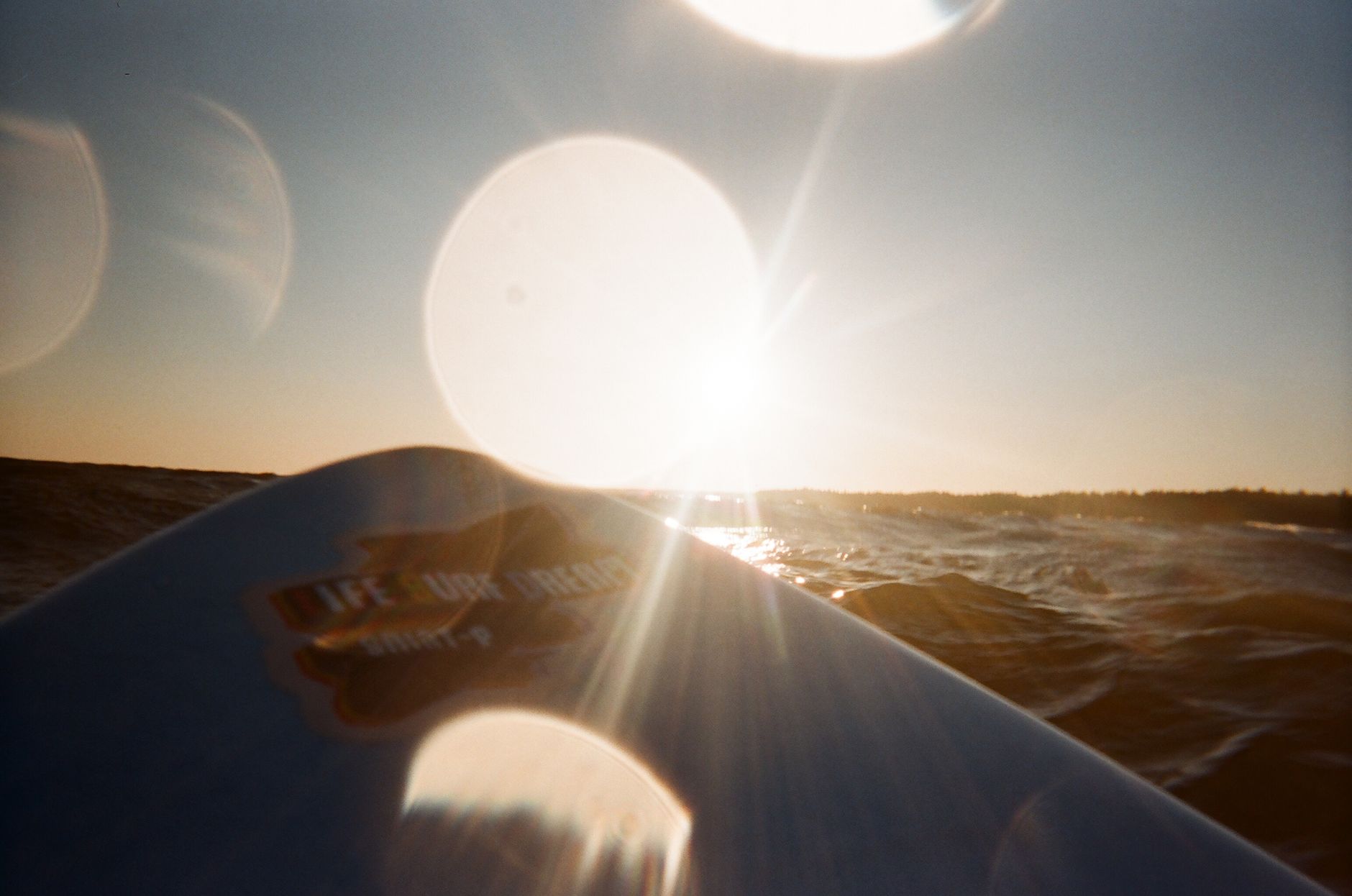 Captivating view of sunset over ocean waves with a surfboard.
