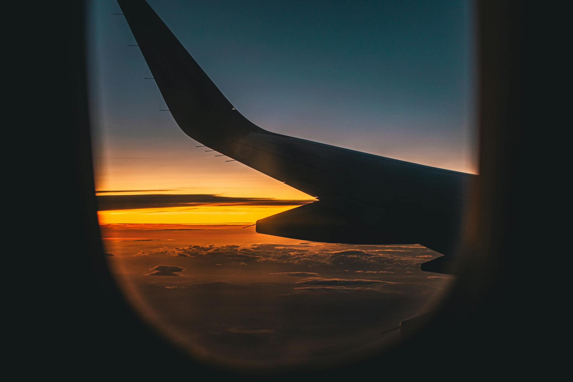 A breathtaking view of an airplane wing against a sunset sky, captured from a window seat.