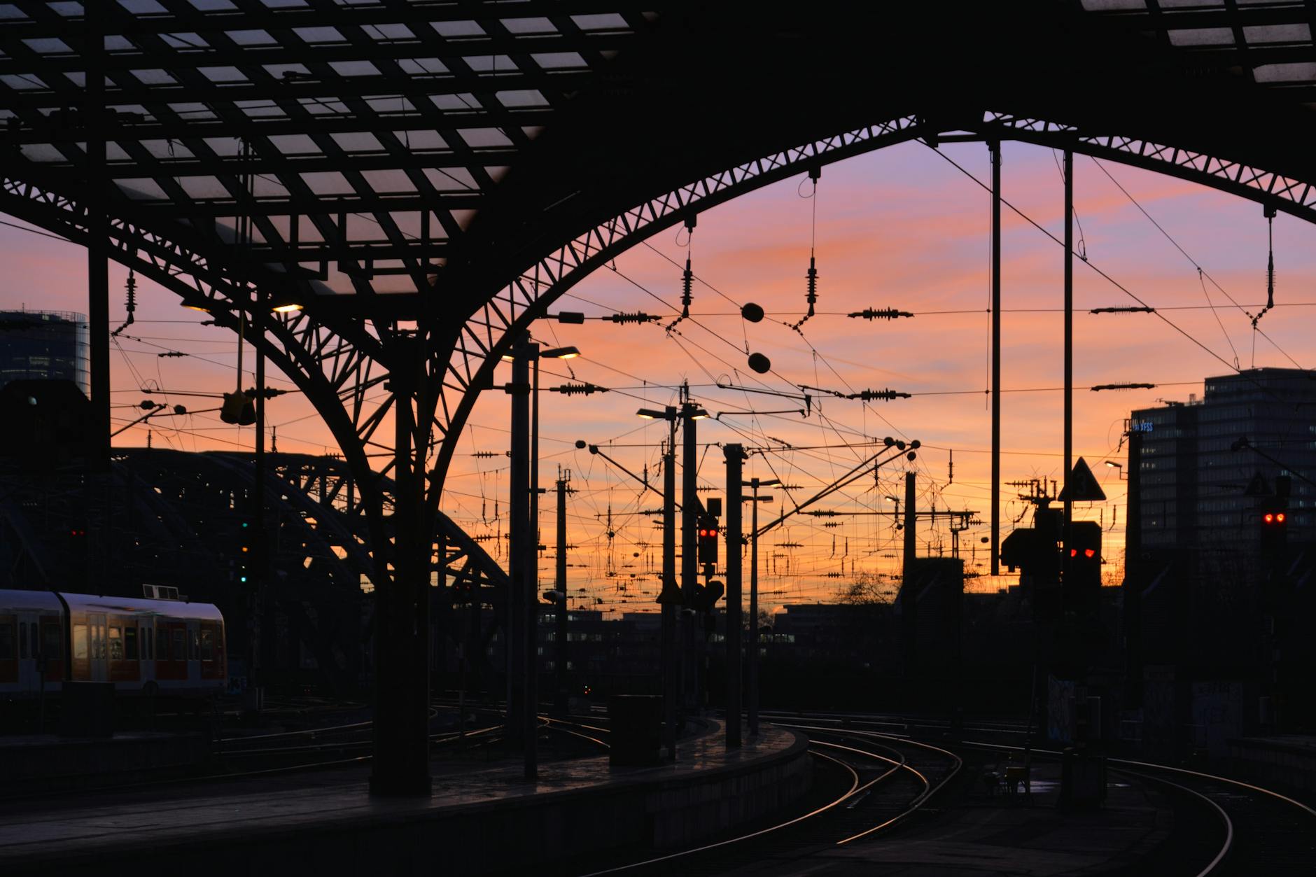 Dramatic sunset view of a railway station silhouette in Germany showcasing structural elegance and evening hues.